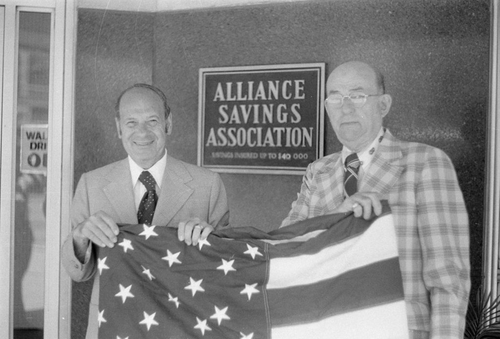 Annunzio holds flag with Chester Wiktorski outside the Alliance Savings and Loan Association