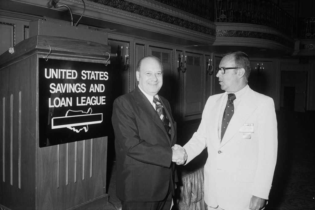 Congressman Frank Annunzio posing in front of US Savings and Loan League Sign