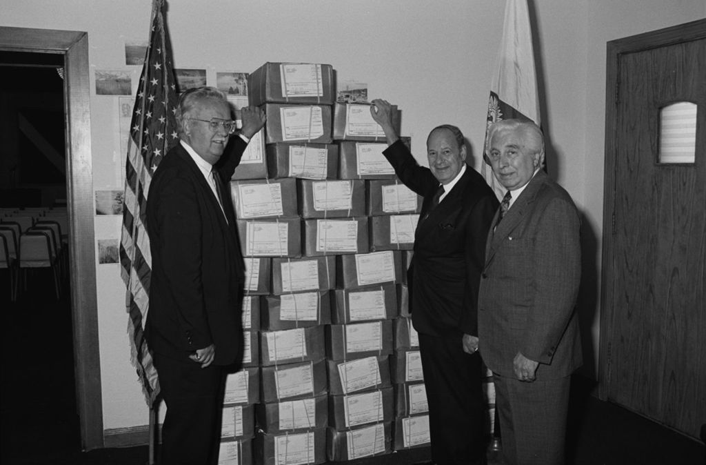 Miniature of President of the Polish National Alliance Al Majewski, Alderman Roman Pucinski, and Congressman Frank Annunzio pose with booklets about the Katyn Forest Massacre
