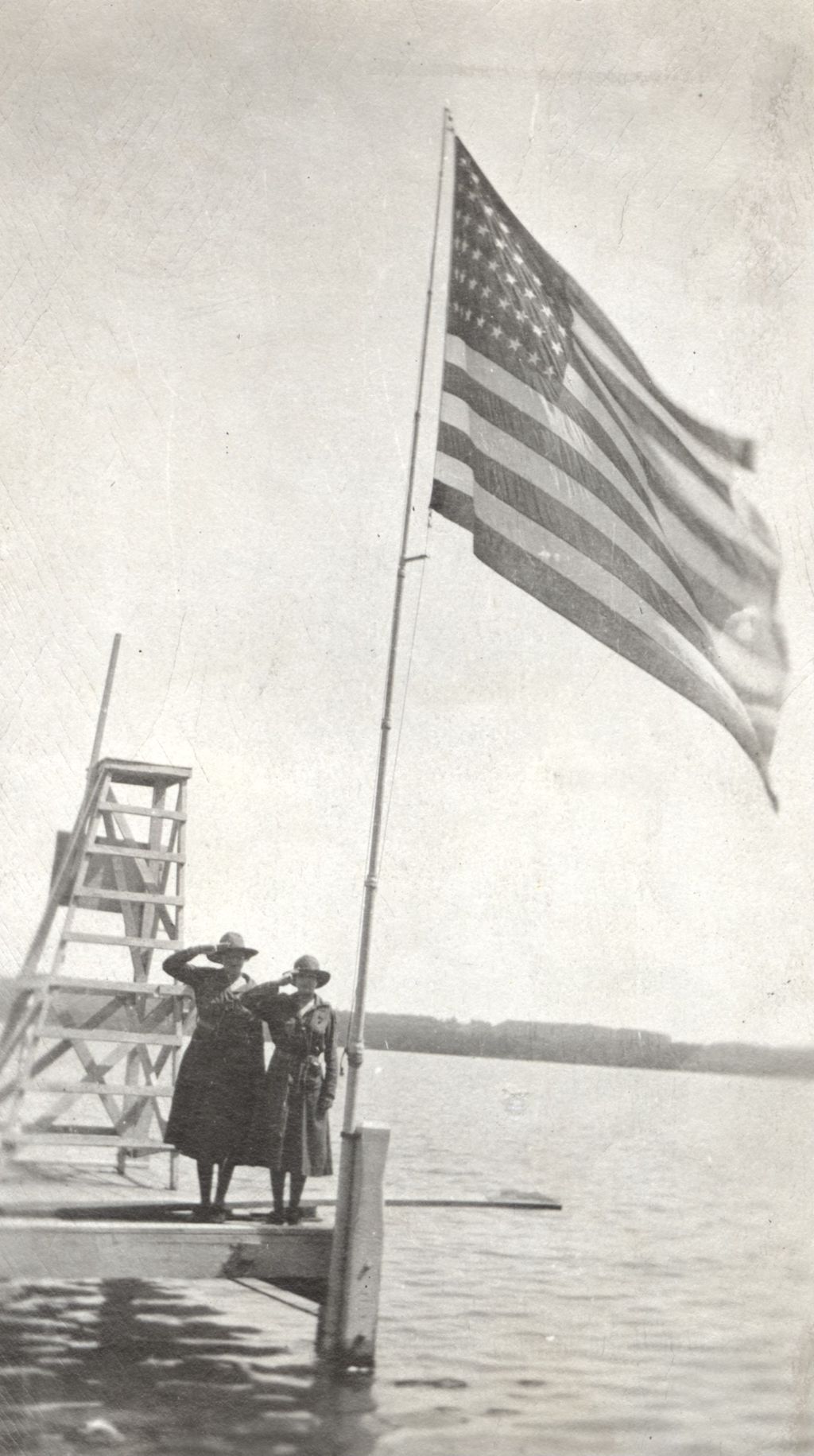 Women in uniforms saluting an American flag