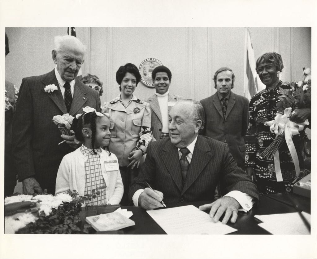 Miniature of Richard J. Daley with young girl, signs document