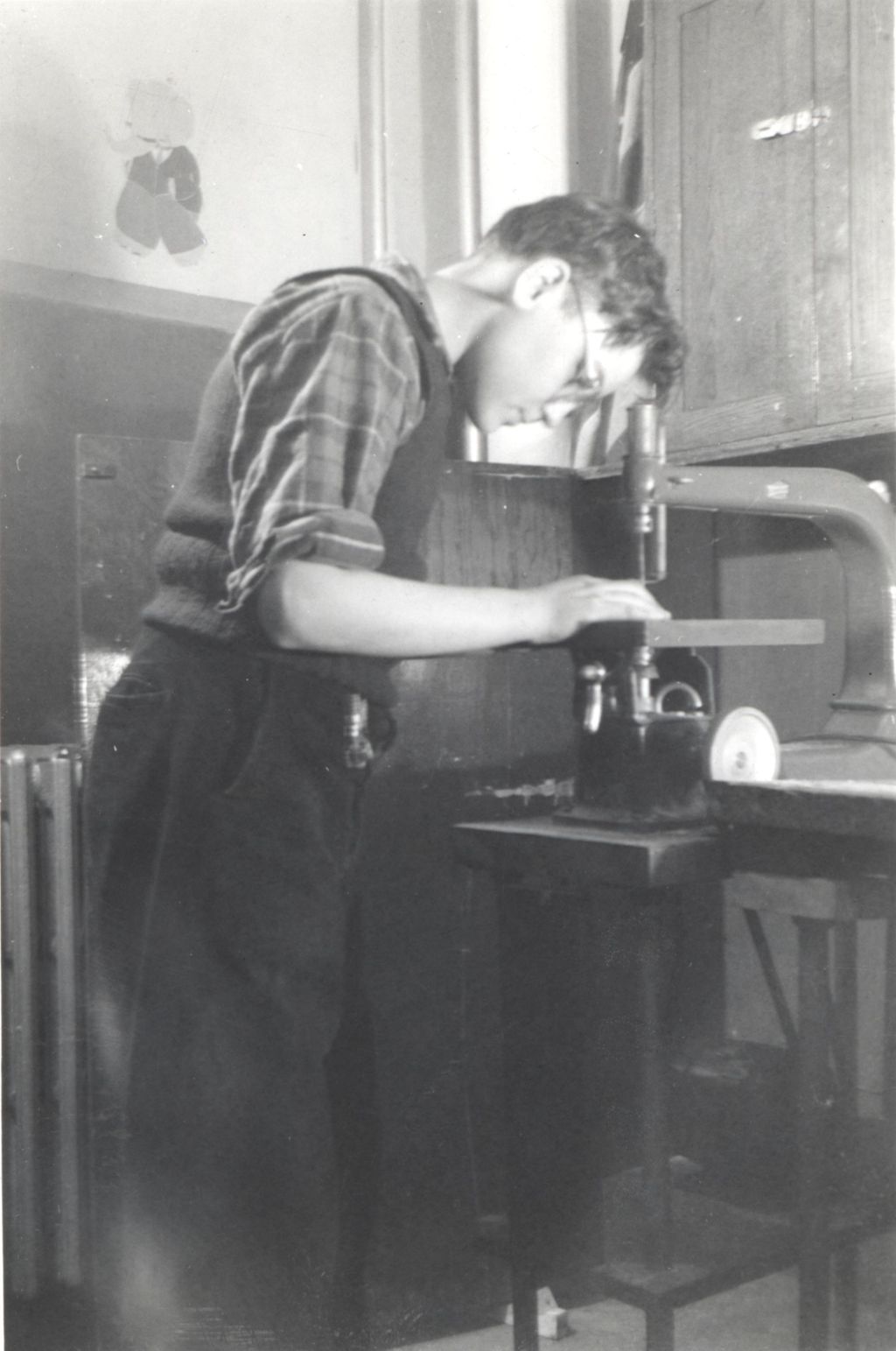 Teenage boy working on drill press in workroom