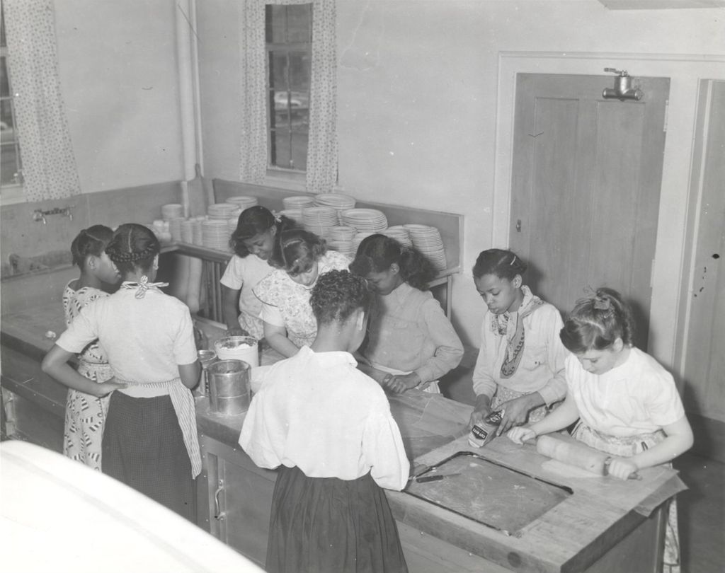 Teenage girls rolling out dough in a kitchen