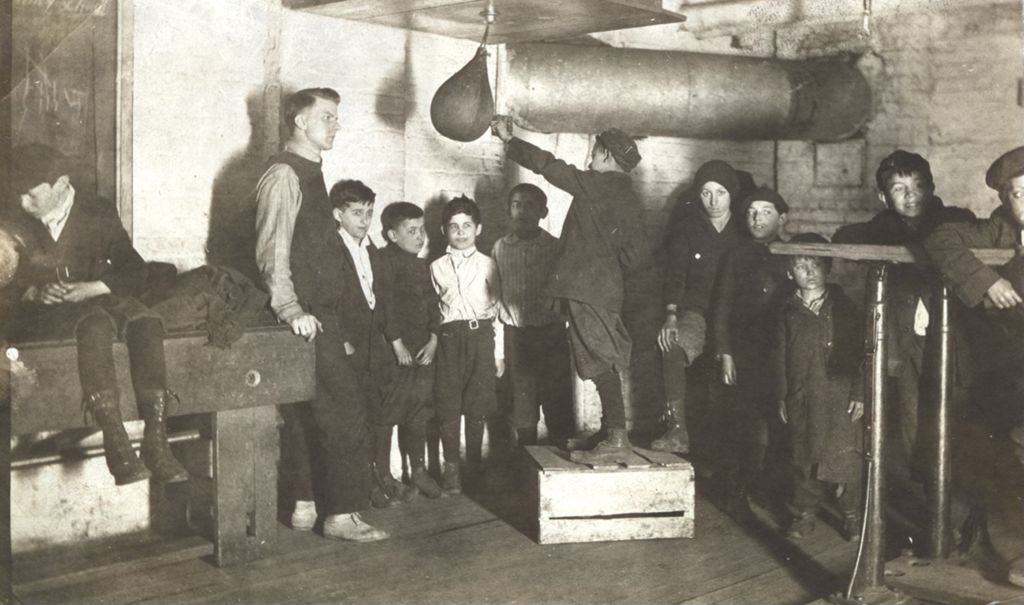 Boy demonstrating a punching bag to young boxers