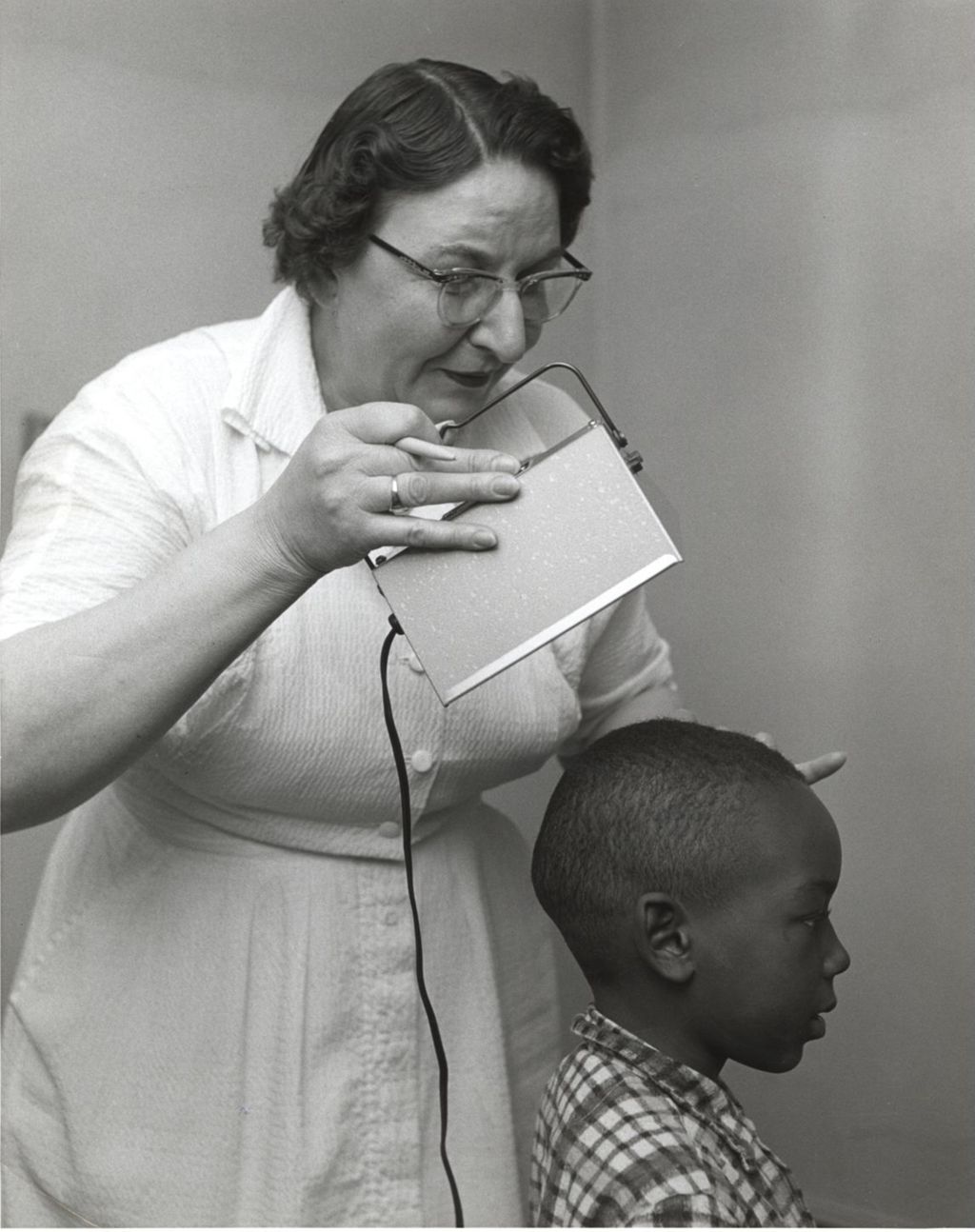Nurse examining head of young boy, Marcy Center Clinic