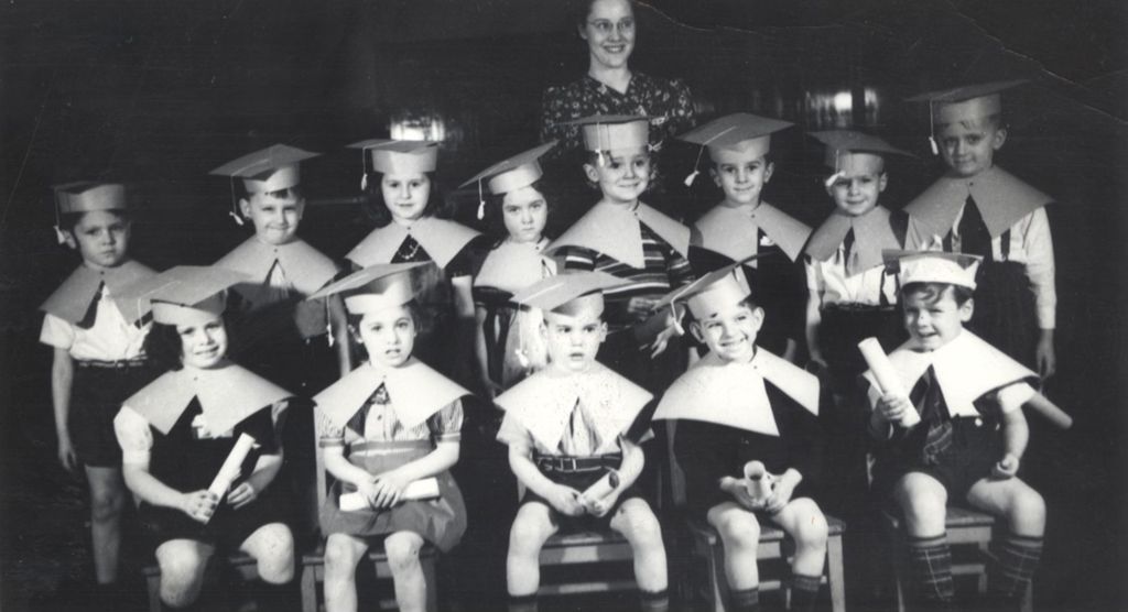 Graduating children with caps and diplomas