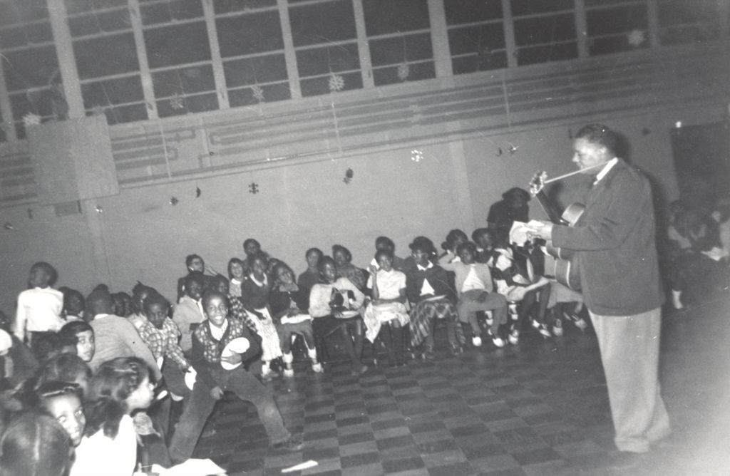 Children listening to guitarist in large room