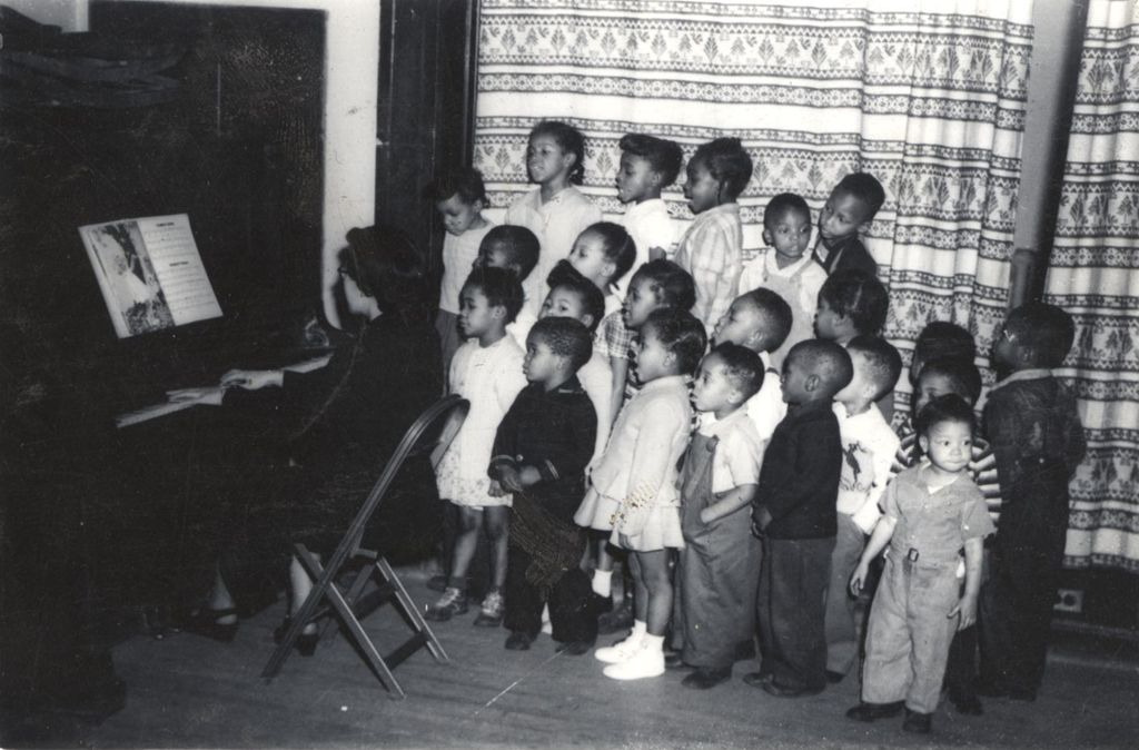 Mary Hata playing piano for singing children