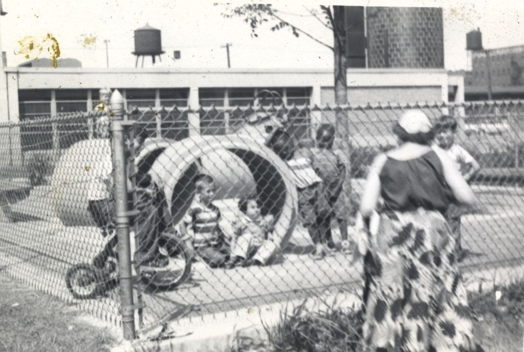 Children playing in concrete pipe segments in a play area