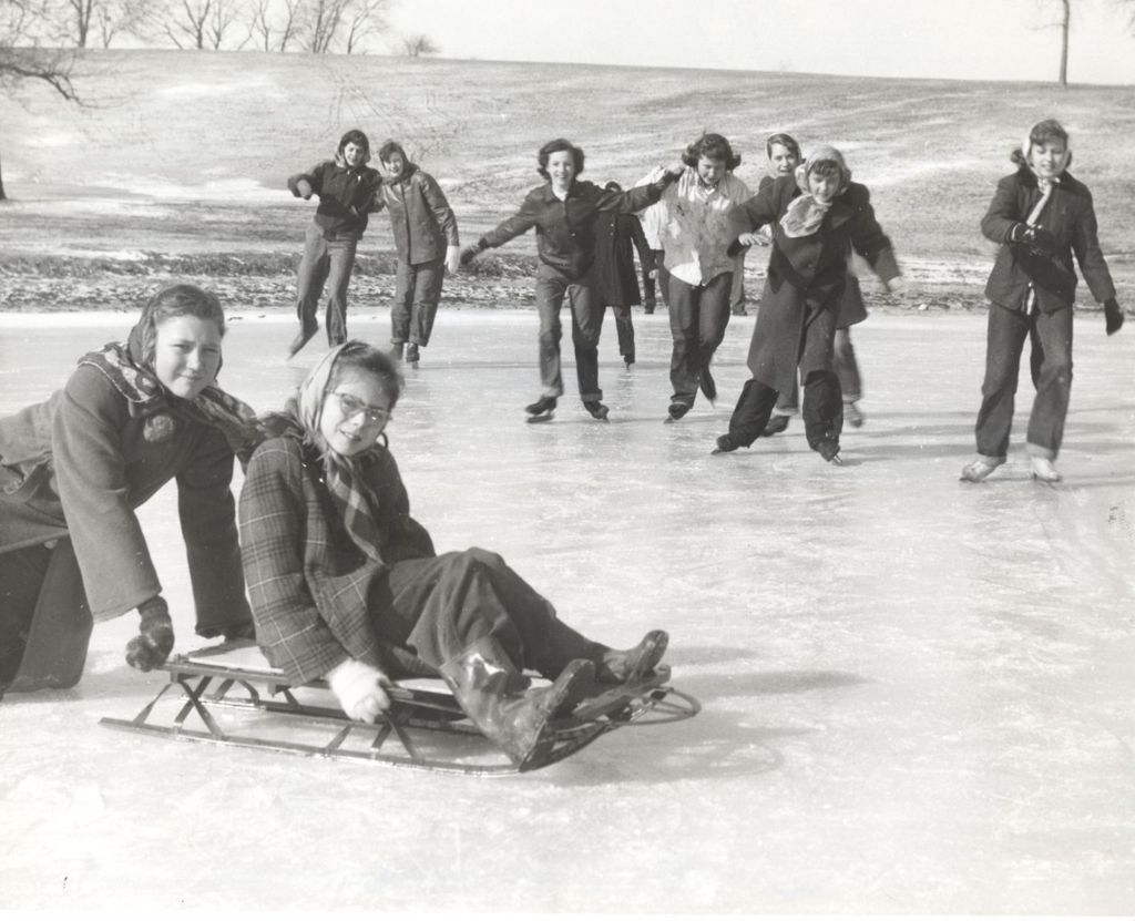 Teenage girls sledding and skating on a pond at Mark Twain Camp