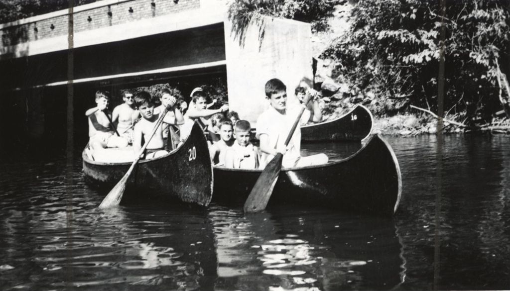 Boys paddling canoes on river