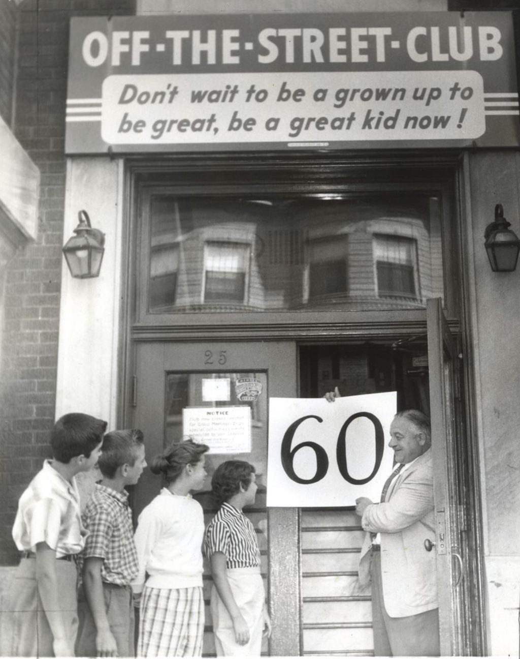Auguste Mathieu holding a "60" sign at Off-The-Street Club entrance
