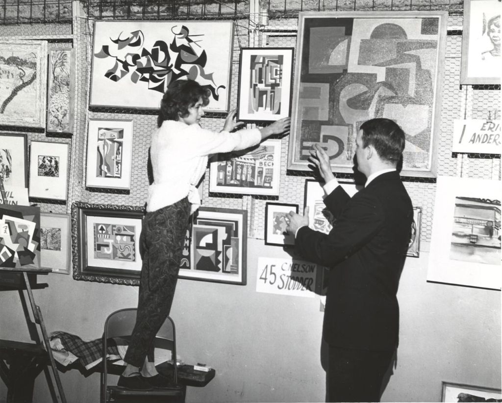 Woman and man hanging artwork for an exhibition