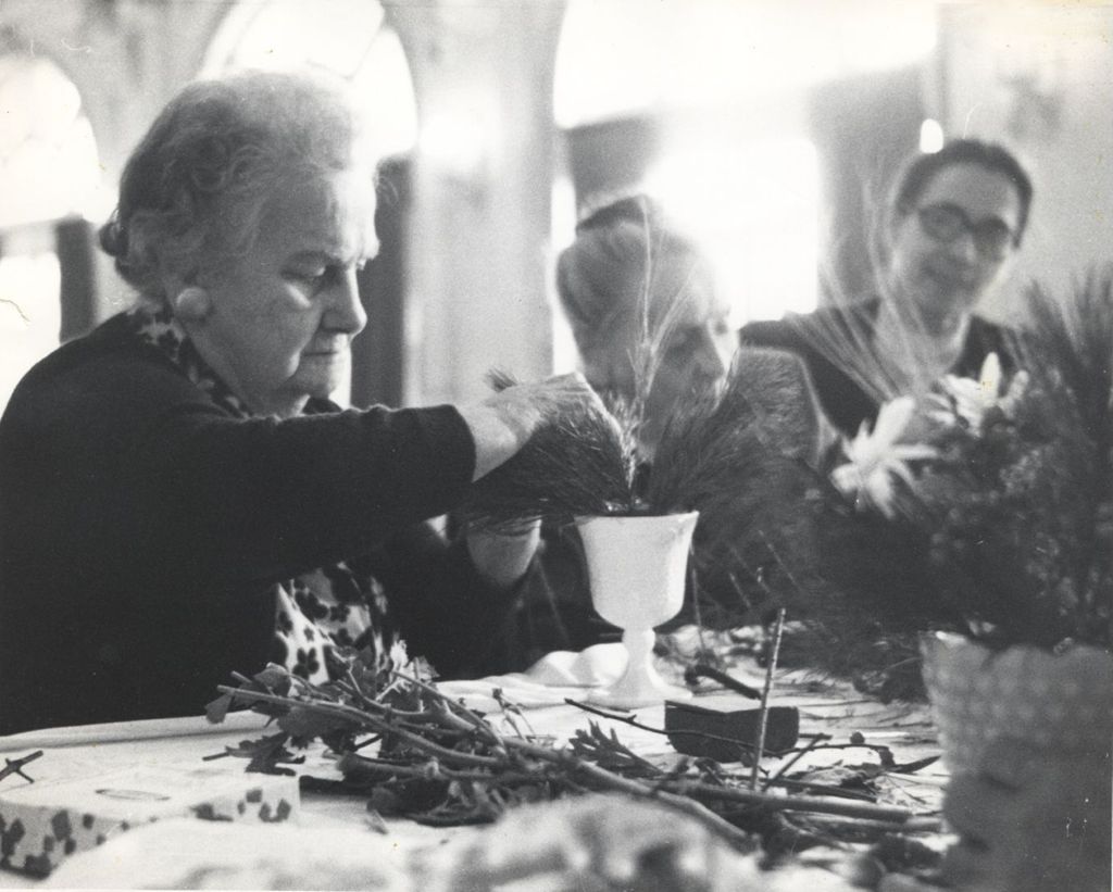 Senior woman arranging evergreens in vase