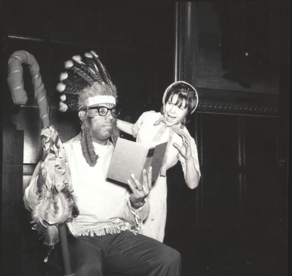 Man wearing Native American headdress and woman in pioneer costume rehearsing for a performance