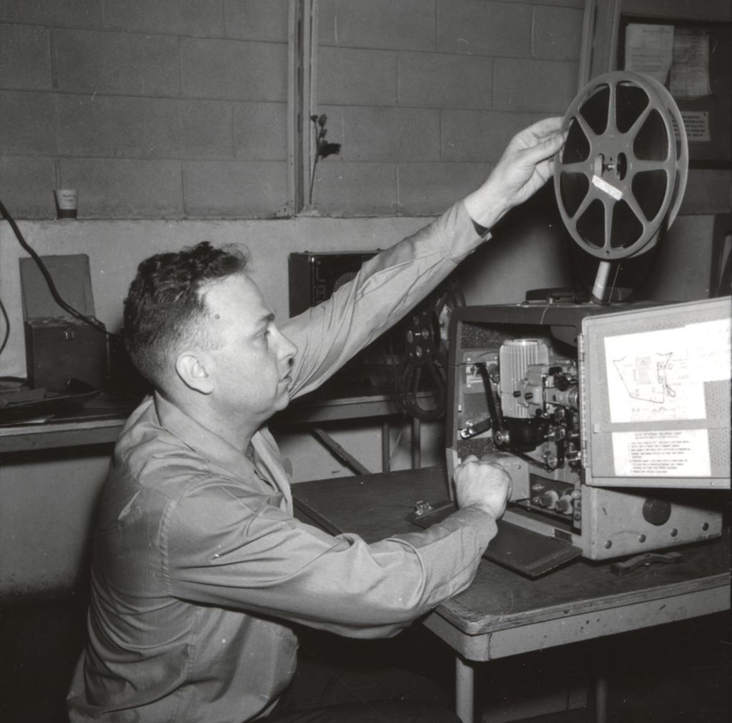 Projectionist adjusting film at "Fun Nite" party