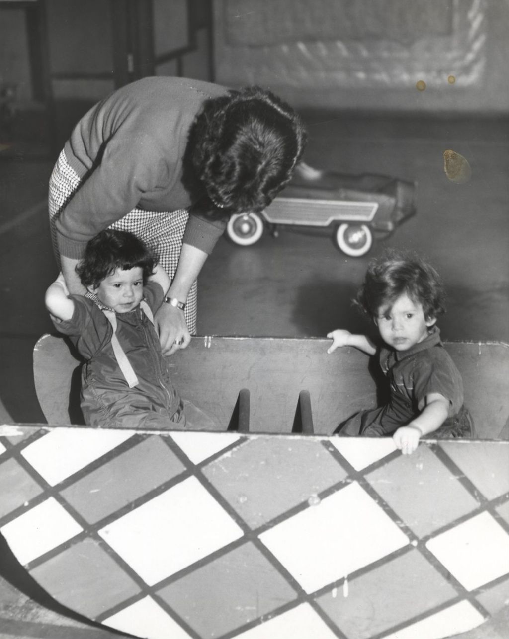 Children playing in a "rocking boat" with a woman watching