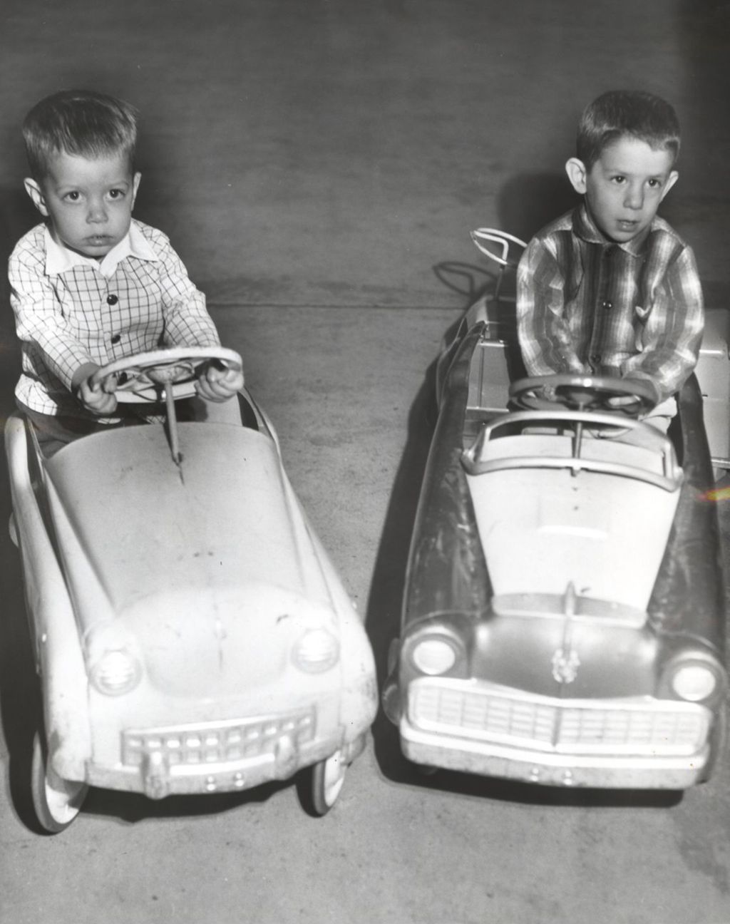 Young boys riding in toy cars