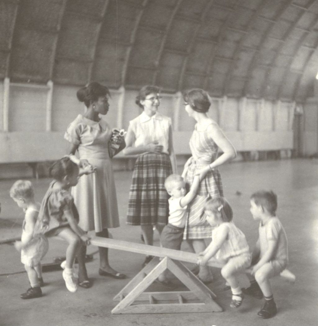 Children playing on a see-saw with women watching