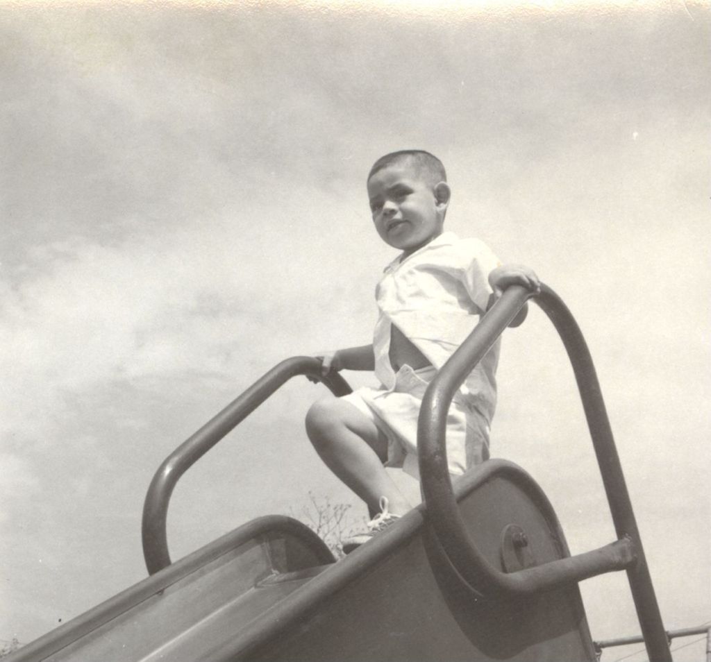Young boy standing atop a slide