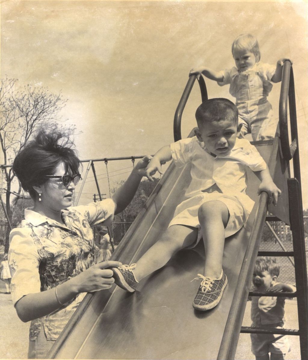 Children playing on a slide with a woman assisting