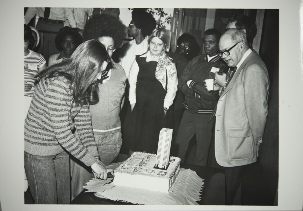 Students cutting a cake at the Decennial Celebration, featuring Chancellor Donald Riddle (at right)