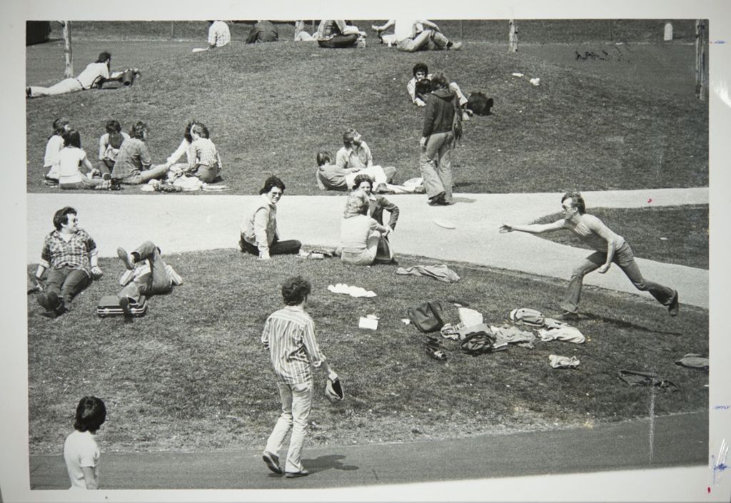 Miniature of Students throwing a frisbee and sitting in the grass on campus