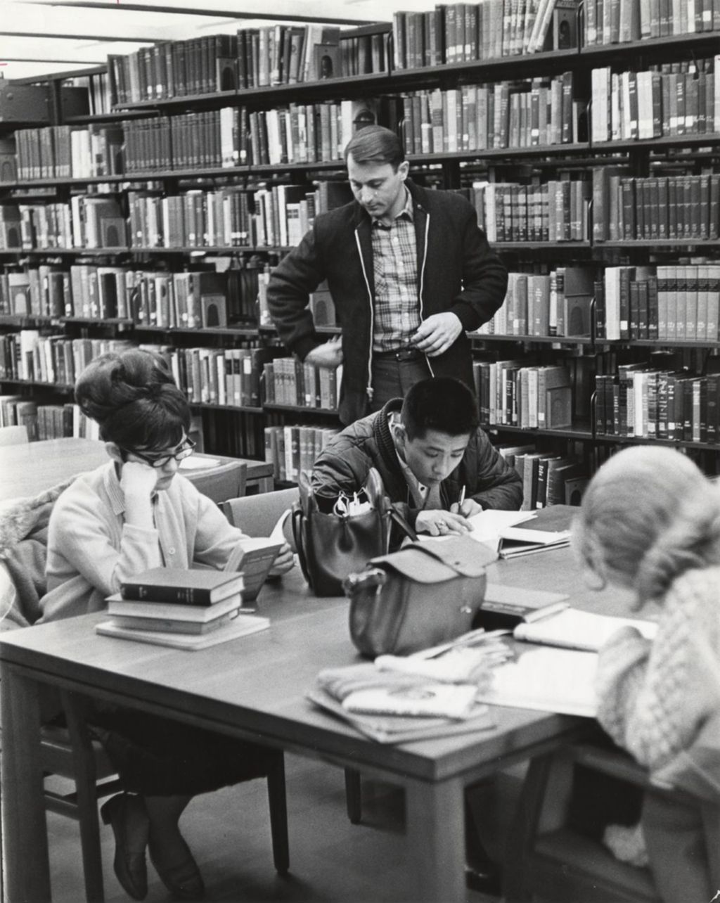 Students sitting at a table behind the stacks at the Richard J. Daley Library