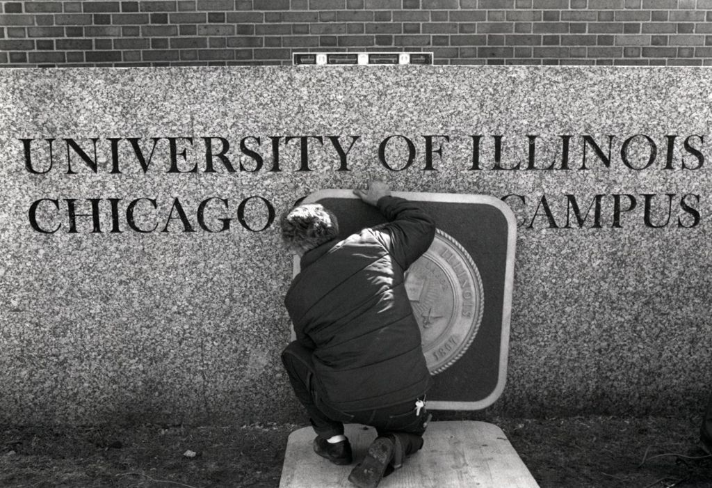 Miniature of Worker affixing the University seal to the main entrance sign