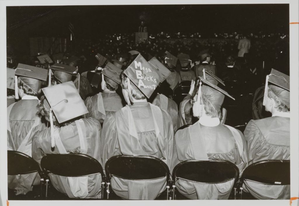 Seated students at the graduation ceremony, one with a decorated mortarboard