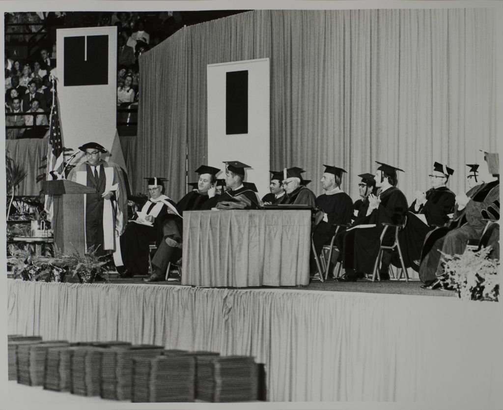 Faculty member inviting University of Illinois President John E. Corbally to the podium, graduation ceremony
