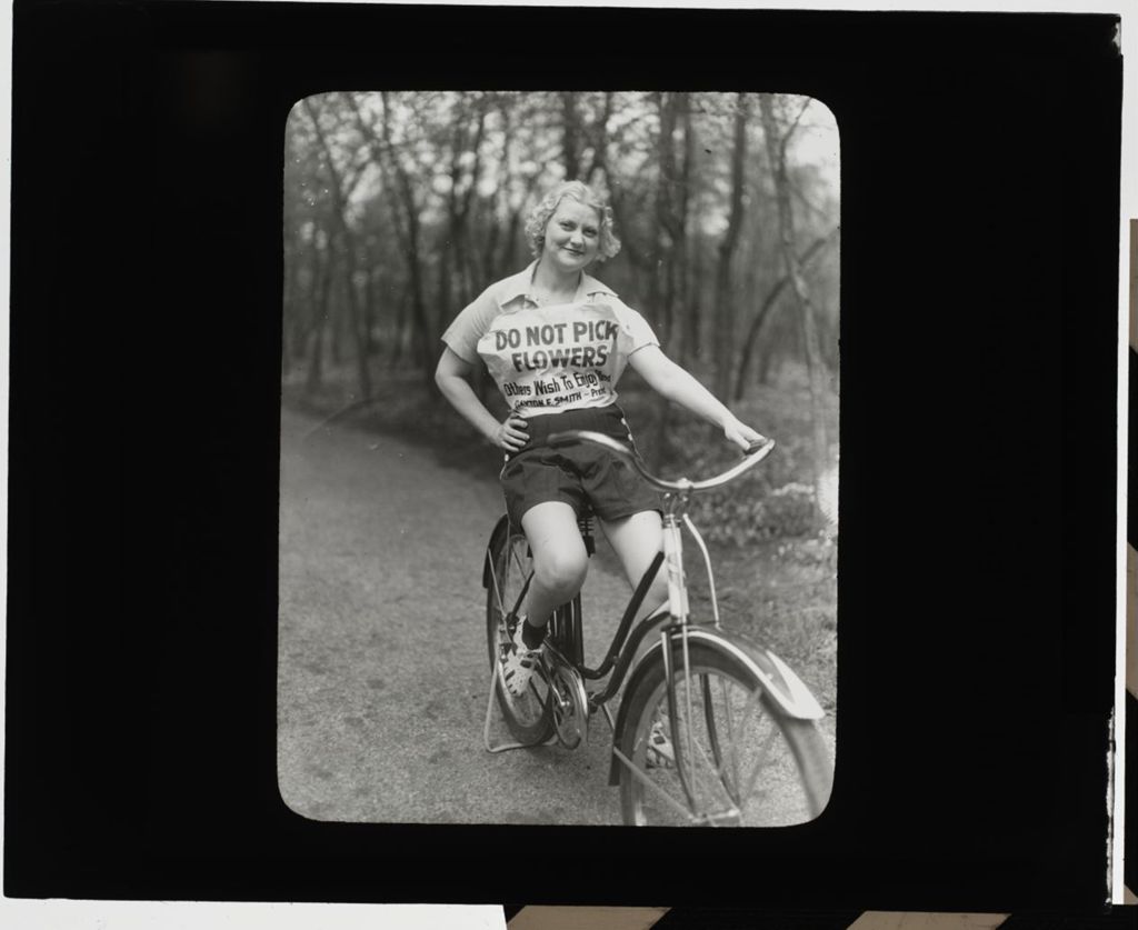 Miniature of Woman on Bicycle, wearing Do Not Pick Flowers sign