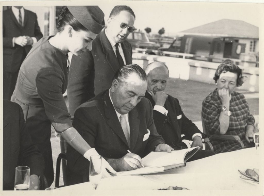 Miniature of Richard J. Daley signing book near airport in Rome