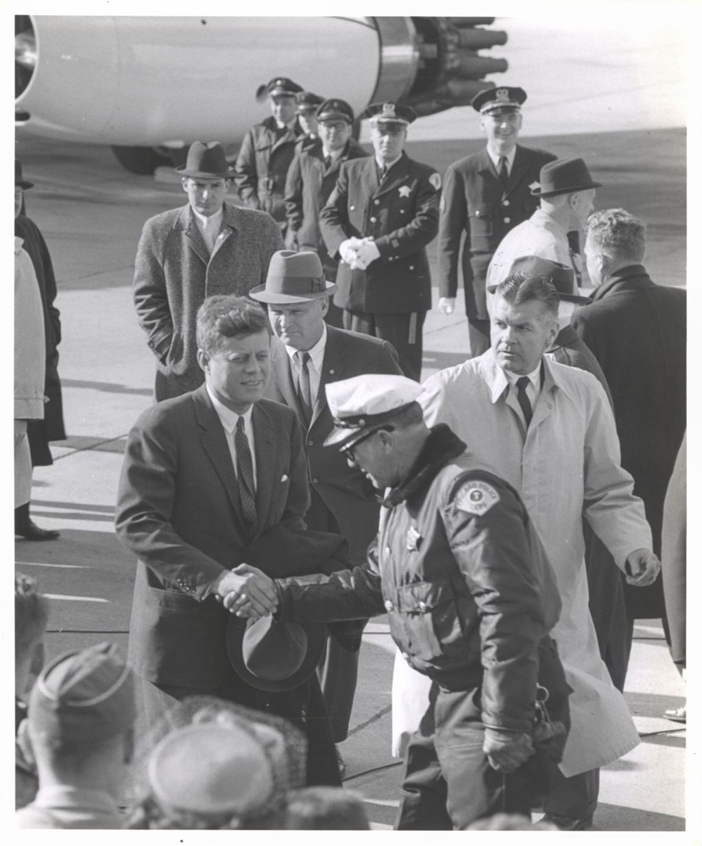 John F. Kennedy greeting a Chicago policeman at O'Hare