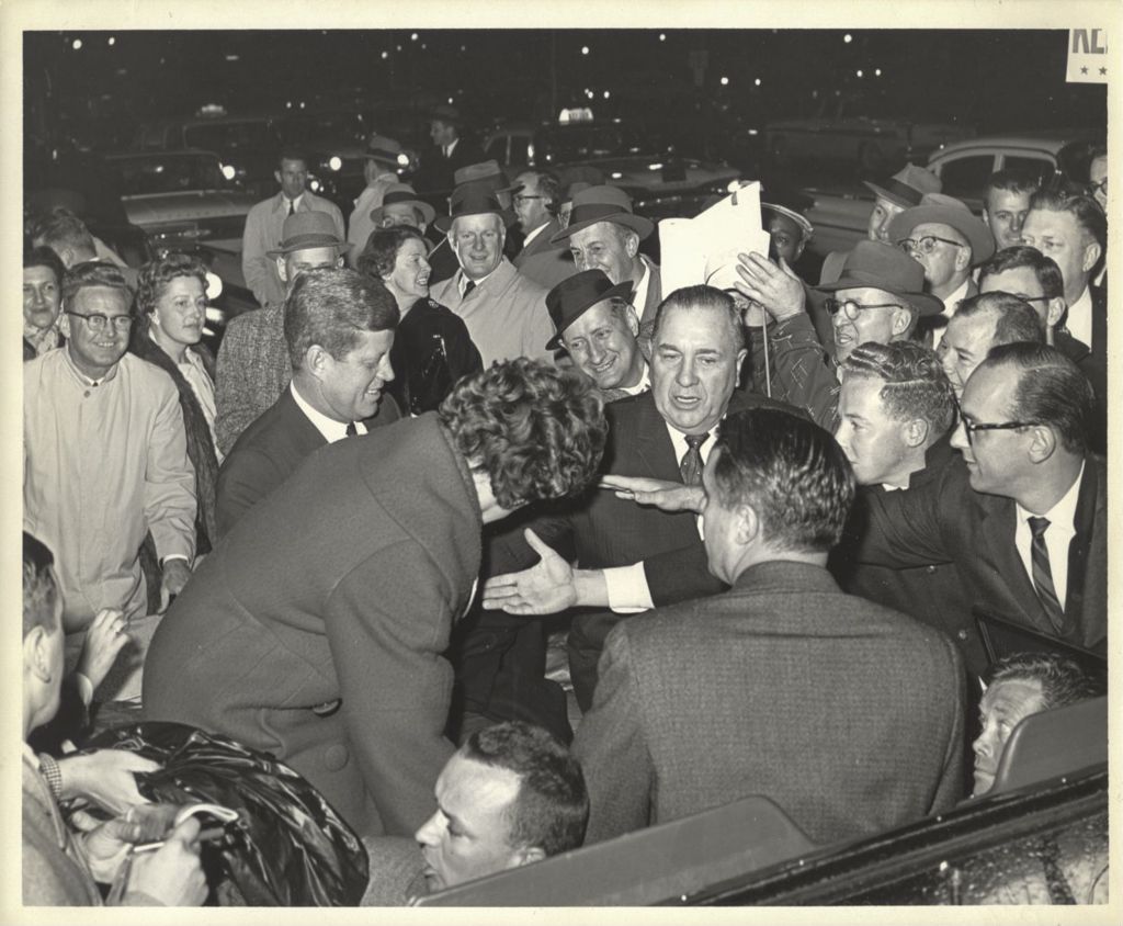 John F. Kennedy and Richard J. Daley surrounded by a crowd during a torchlight parade