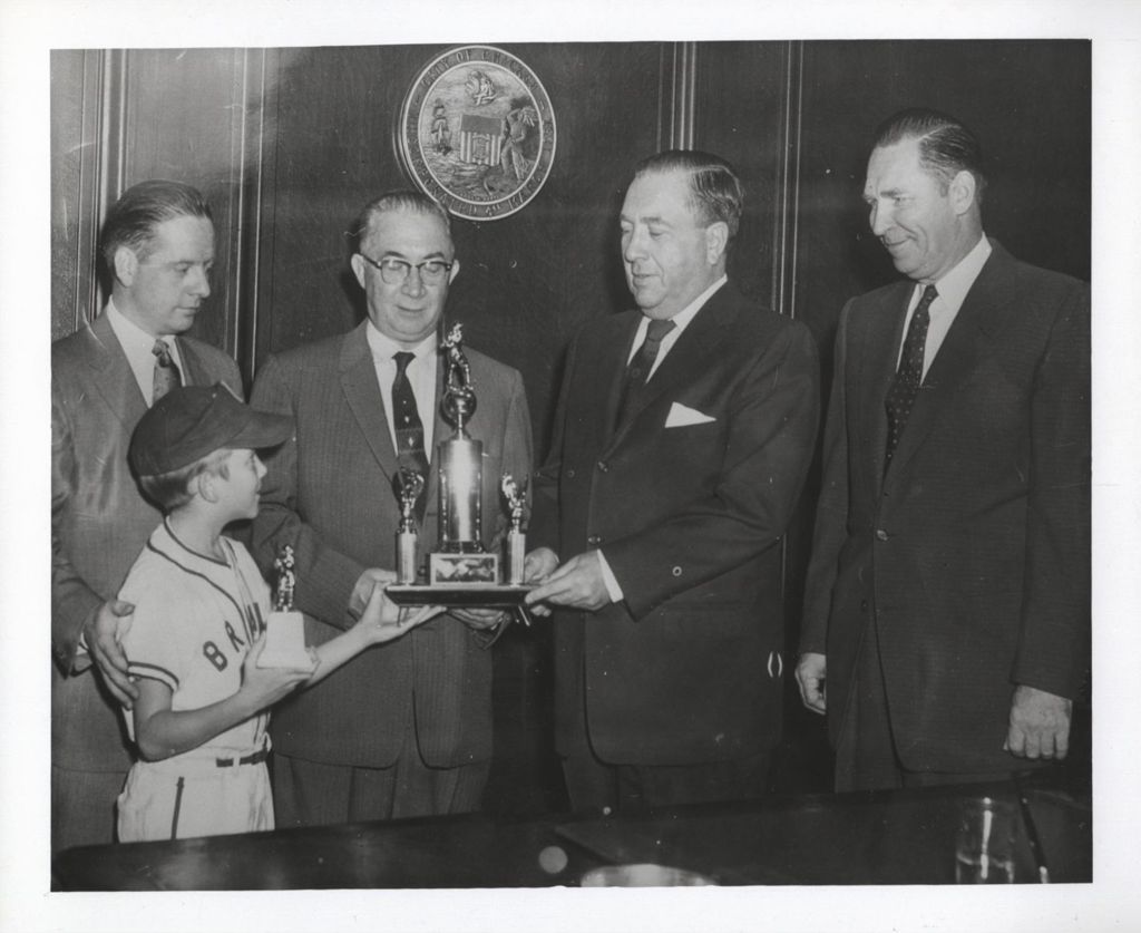 Richard J. Daley presenting a baseball trophy to a young boy