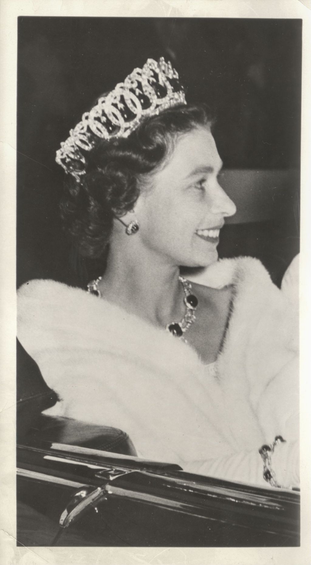 Queen Elizabeth II in an open car wearing formal attire