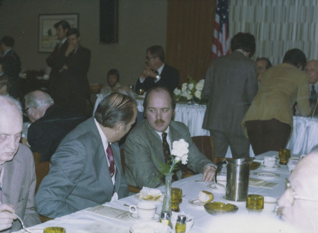 Miniature of Michael Daley and a man seated at a banquet table