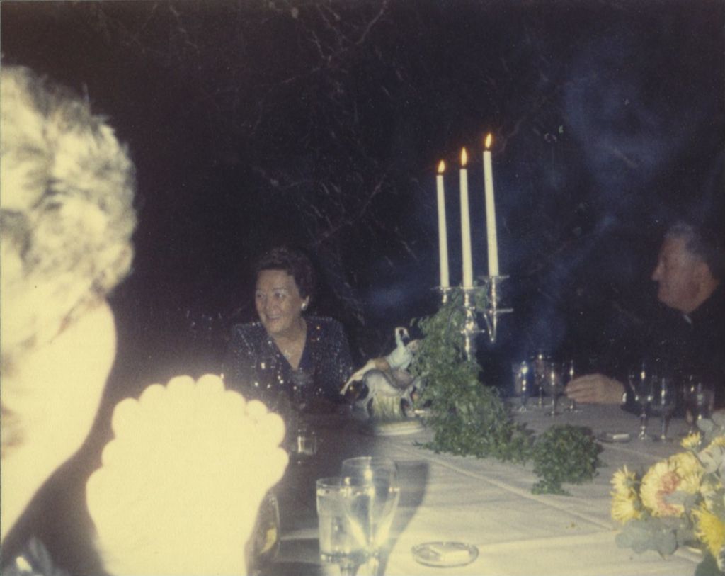 Eleanor Daley and a priest seated at a banquet table