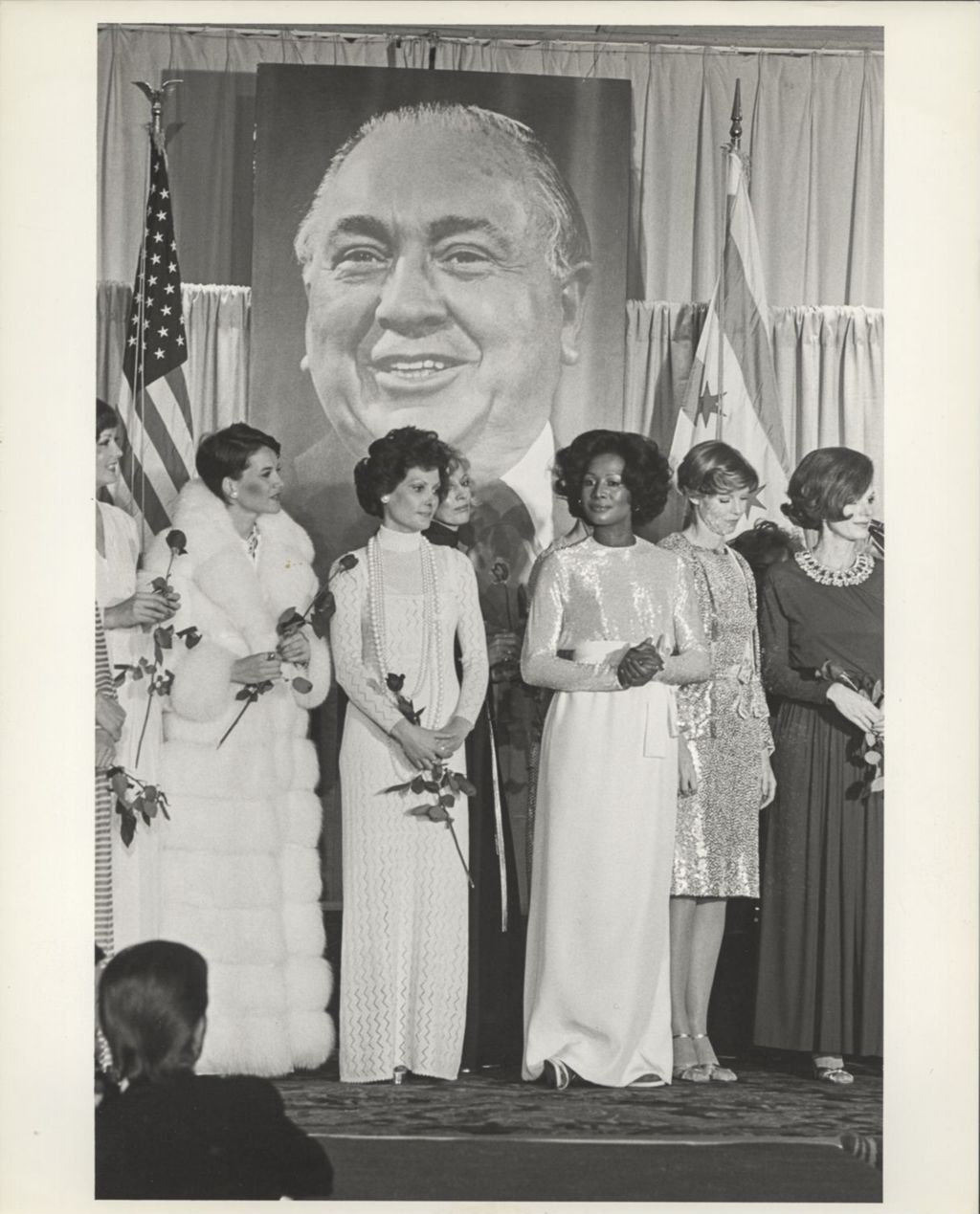 Group of women modeling in front of a portrait of Richard J. Daley