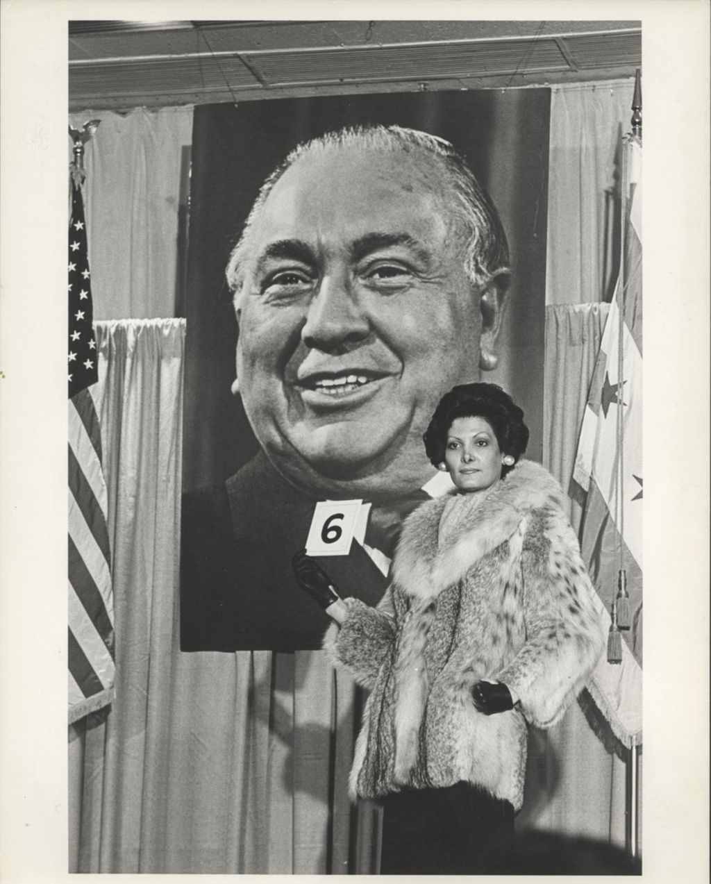 Woman modeling a fur coat in front of a Richard J. Daley portrait