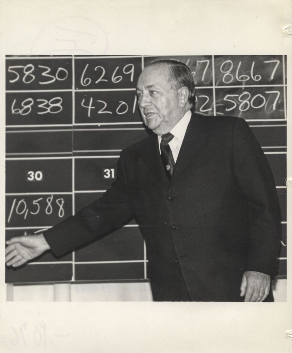 Miniature of Richard J. Daley in front of a blackboard of election tallies during a "We Care" election event