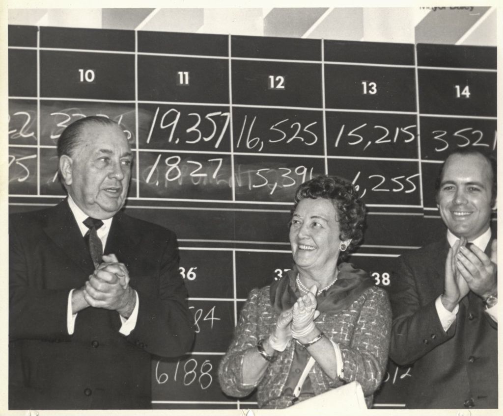 Miniature of Richard J., Eleanor, and Richard M. Daley in front of a blackboard of election tallies at "We Care" election event