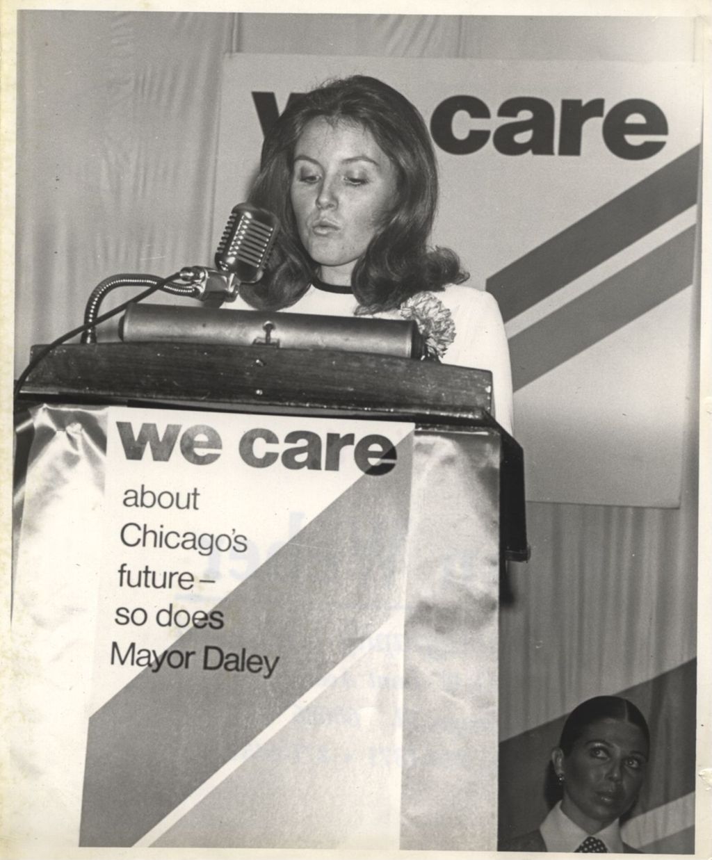 Woman speaking at a podium at a "We Care" event