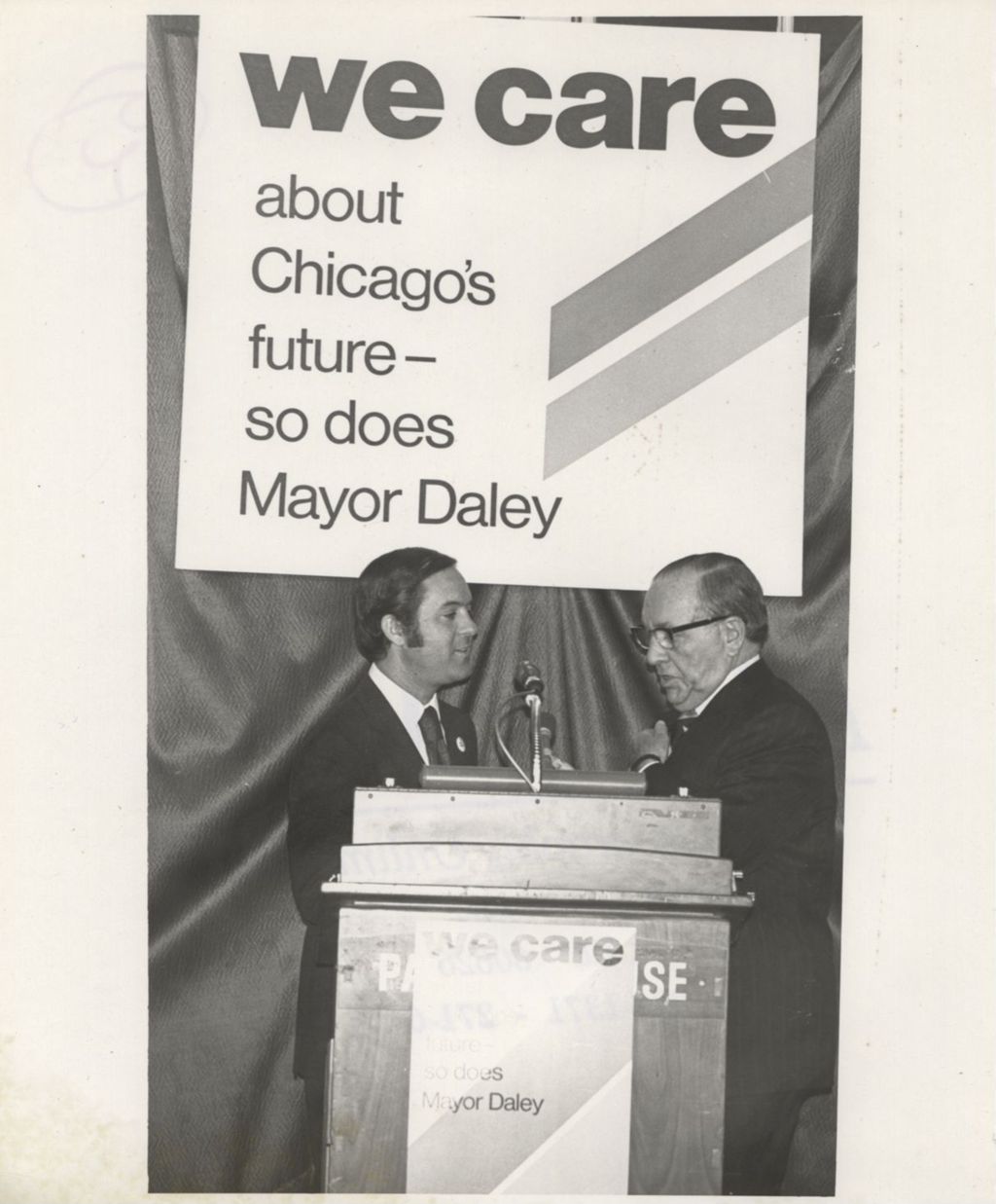 Miniature of Richard J. Daley behind a podium at a "We Care" event