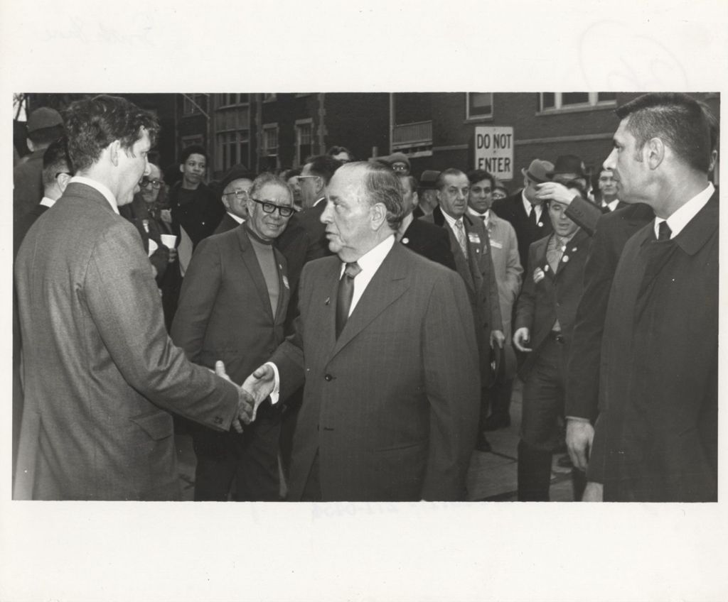 Miniature of Richard J. Daley shaking hands at an outdoor "We Care" event
