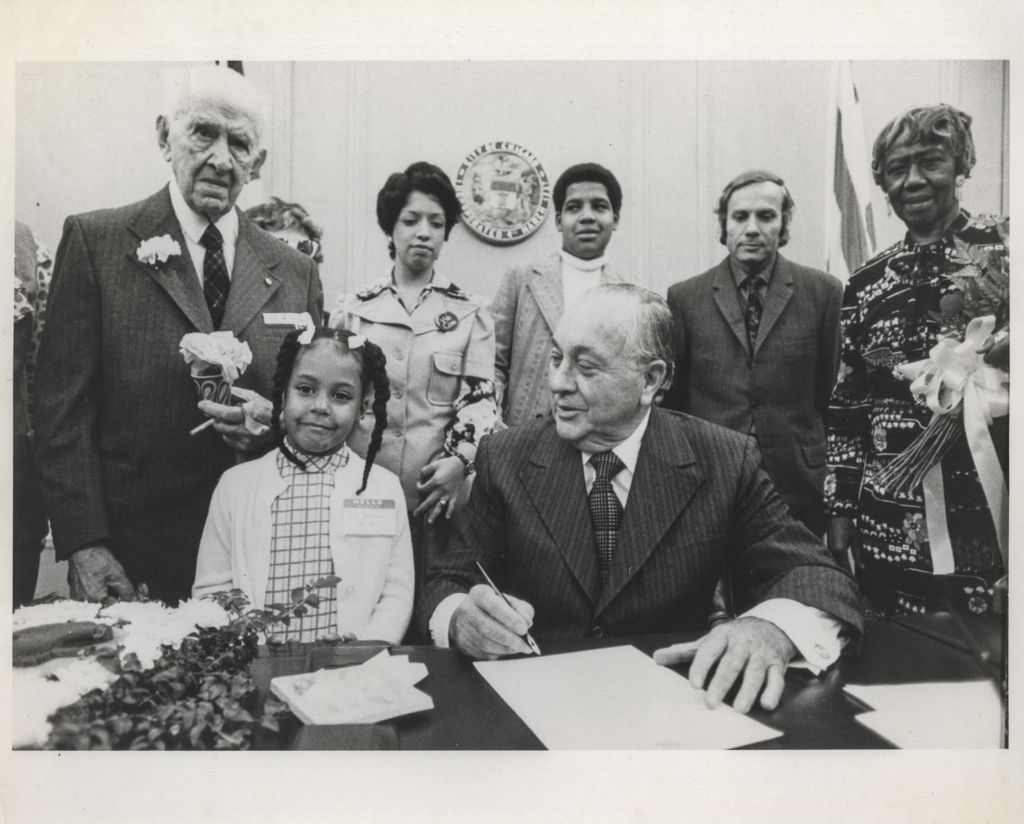 Richard J. Daley with young girl, signs document