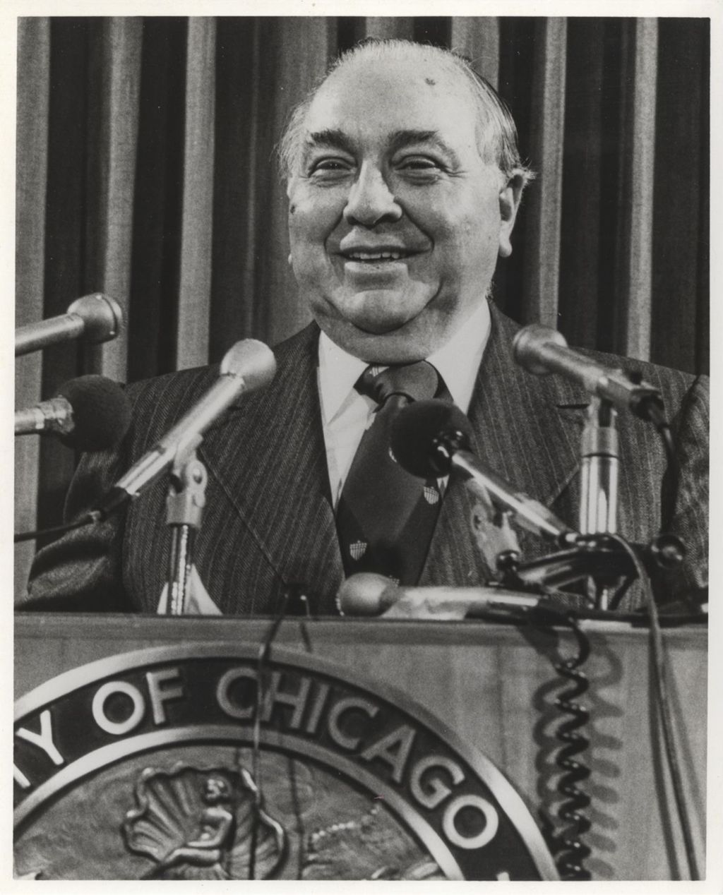 Miniature of Richard J. Daley smiling behind a podium
