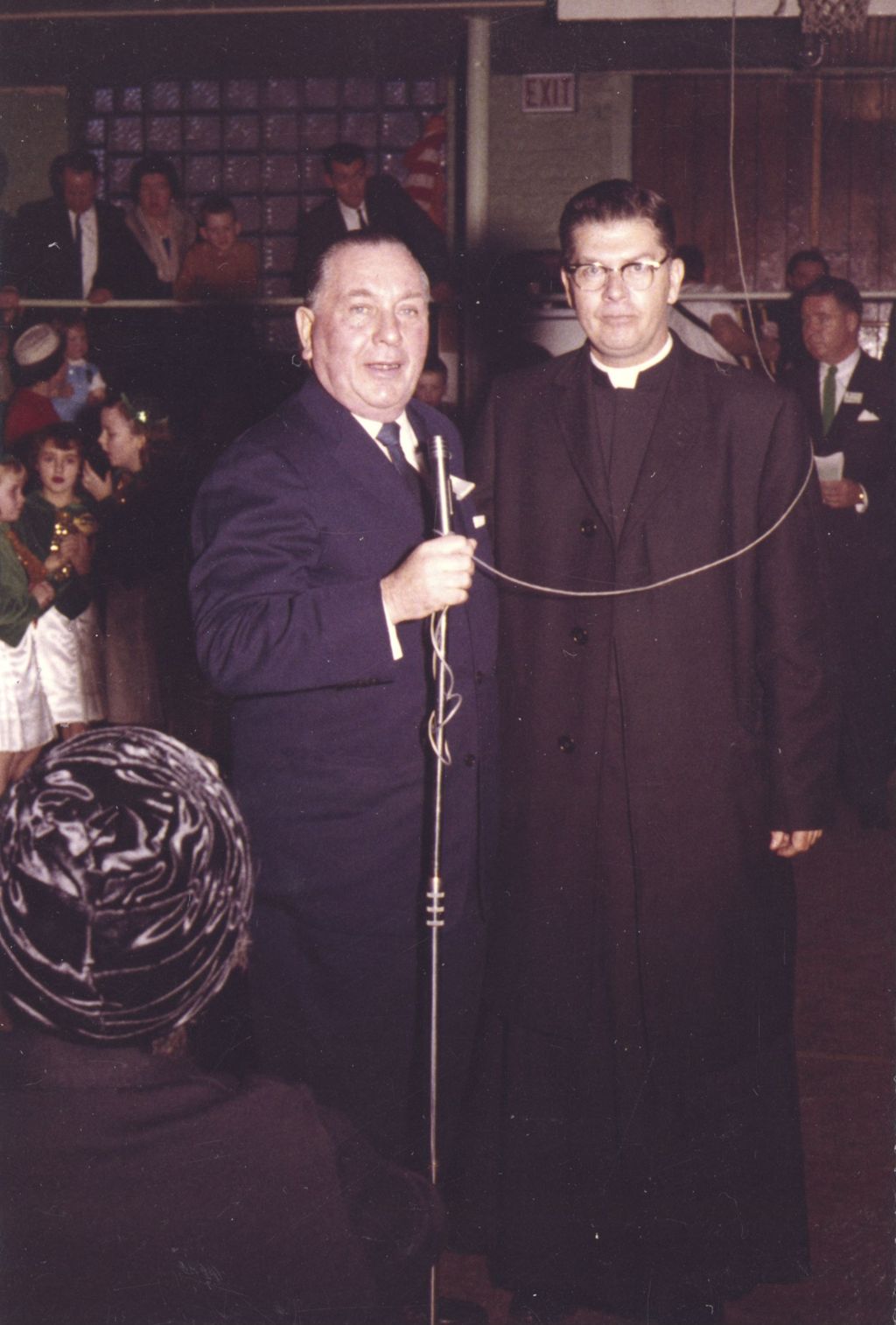 Richard J. Daley at a microphone with a priest