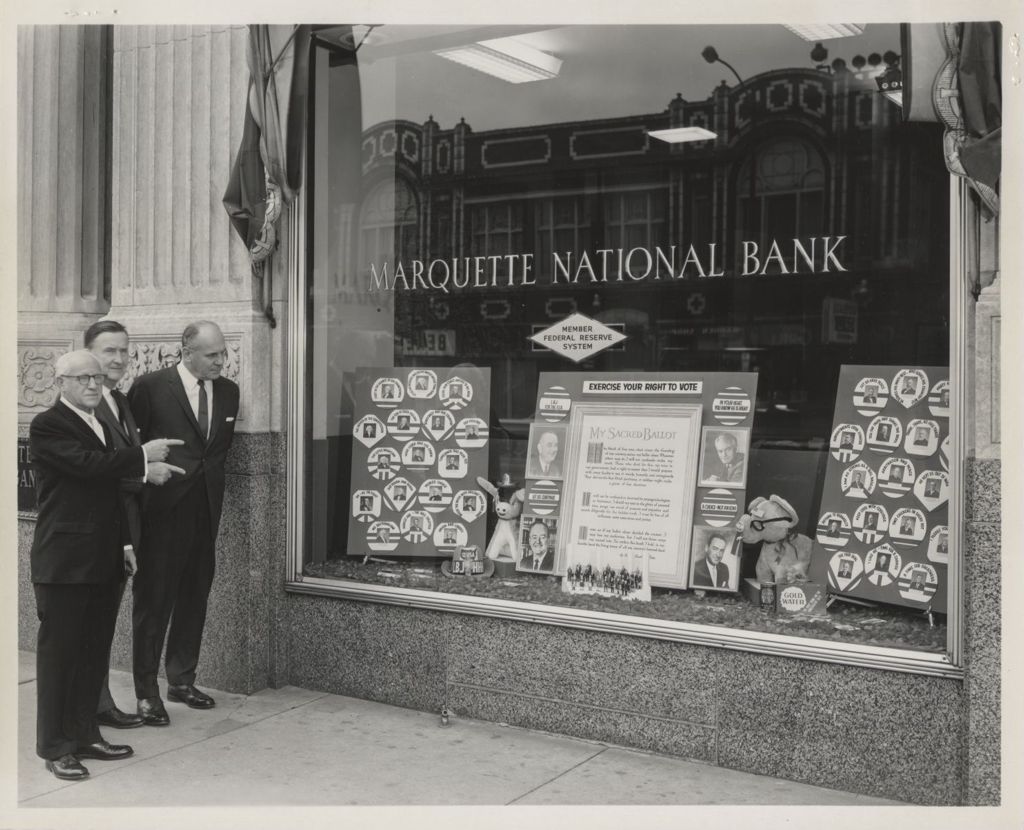 Election Officials and bank president view bank window display on voting